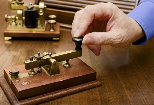 A hand manipulating an old morse transmitter